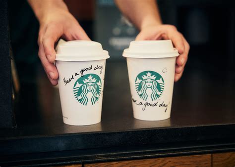 Coffee cups from Starbucks and a local cafe placed side by side on a table for comparison.