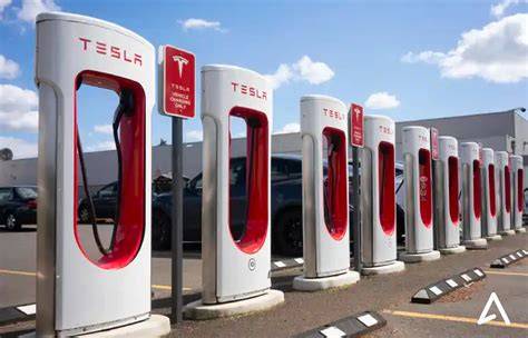 A Tesla electric car parked at a Tesla service center next to a Supercharger charging station.