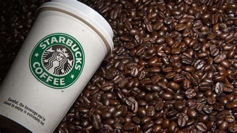 A Starbucks coffee cup surrounded by Arabica coffee beans emphasizing quality.
