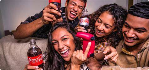 A group of people watching a Coca-Cola advertisement on a large screen and drinking Coca-Cola sodas